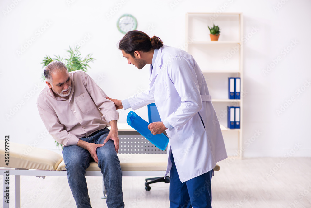 Obraz premium Stary pacjent odwiedzający młodego lekarza płci męskiej