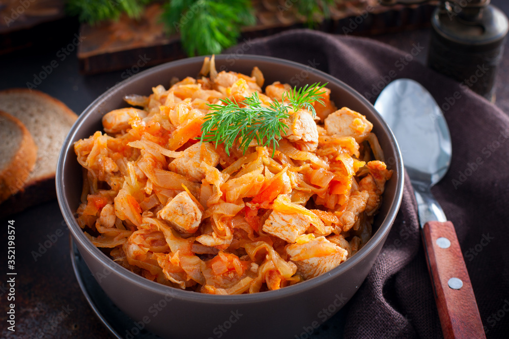 Braised cabbage with chicken breast in a clay bowl, selective focus Braised cabbage with chicken breast in a clay bowl, selective focus