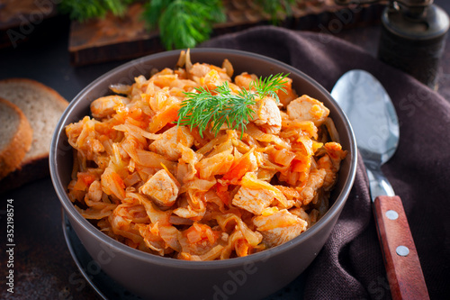 Braised cabbage with chicken breast in a clay bowl, selective focus
