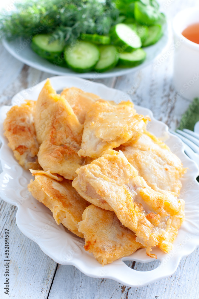 Pollock fillet in batter on a white plate, selective focus Pollock fillet in batter on a white plate, selective focus