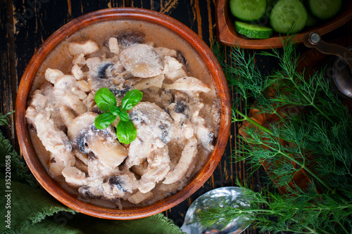 Stroganoff with chicken and mushrooms in a wooden bowl, selective focus