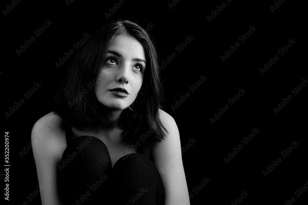 Naklejka premium Black and white young woman looking at camera isolated on black background. Beautiful woman portrait.