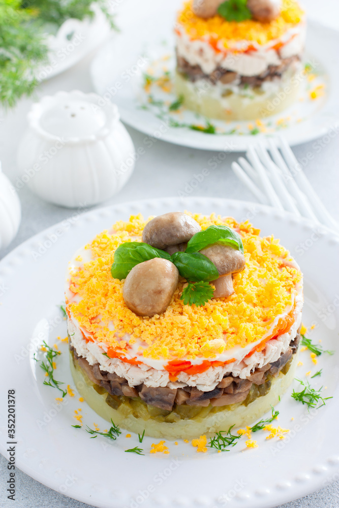 Beautiful festive layered salad with chicken, potatoes, carrots, pickles and fried champignons, selective focus Beautiful festive layered salad with chicken, potatoes, carrots, pickles and fried champignons, selective focus