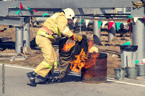 Extinguishing a major fire. A professional fireman in a special suit extinguishes an open fire with. Regional fire-fighting exercise in the training area with urban and contract firefighters.