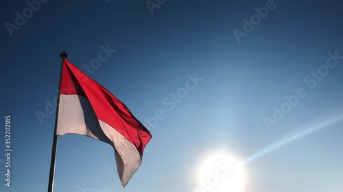 Monaco red white flag is waving against blue sky in the evening sunset. Port Fontvieille, Monaco Ville, azure water, harbor, yachts in Port Hercules, Monaco.