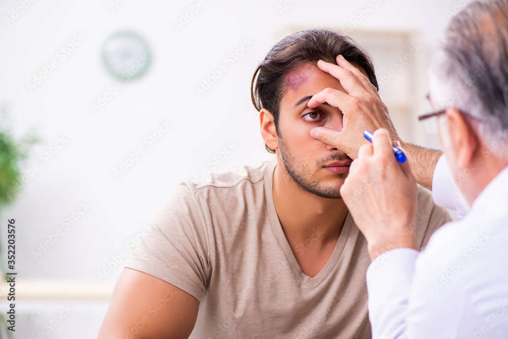 Young face injured man visiting experienced male doctor traumato - obrazy, fototapety, plakaty 