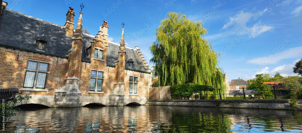 Beautiful ancient building and tree at the canal in Brugge. Belgium. Banner edition.