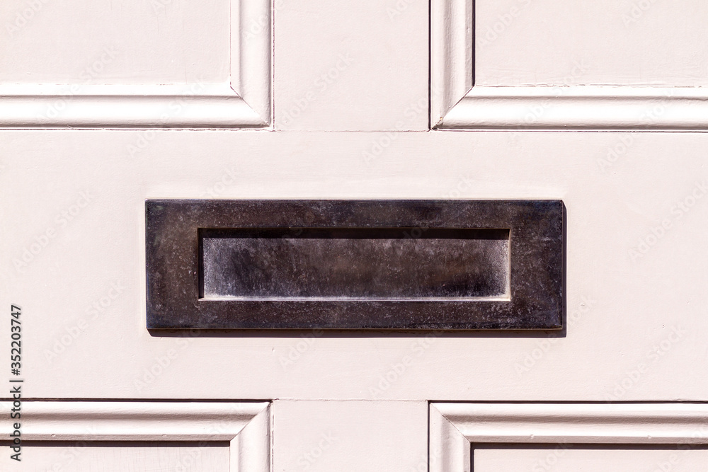 Polished steel letterbox on whit wooden front door Polished steel letterbox on whit wooden front door