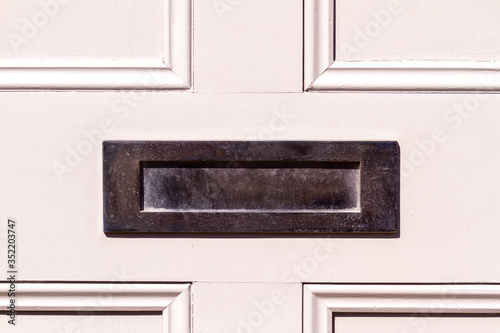Polished steel letterbox on whit wooden front door