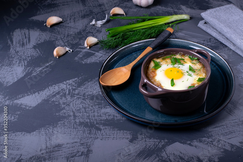 Garlic bread soup with egg baked in the oven in a portion saucepan. Copy space photo