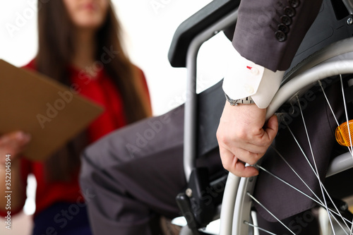 Man in suit on wheelchair communicates with woman