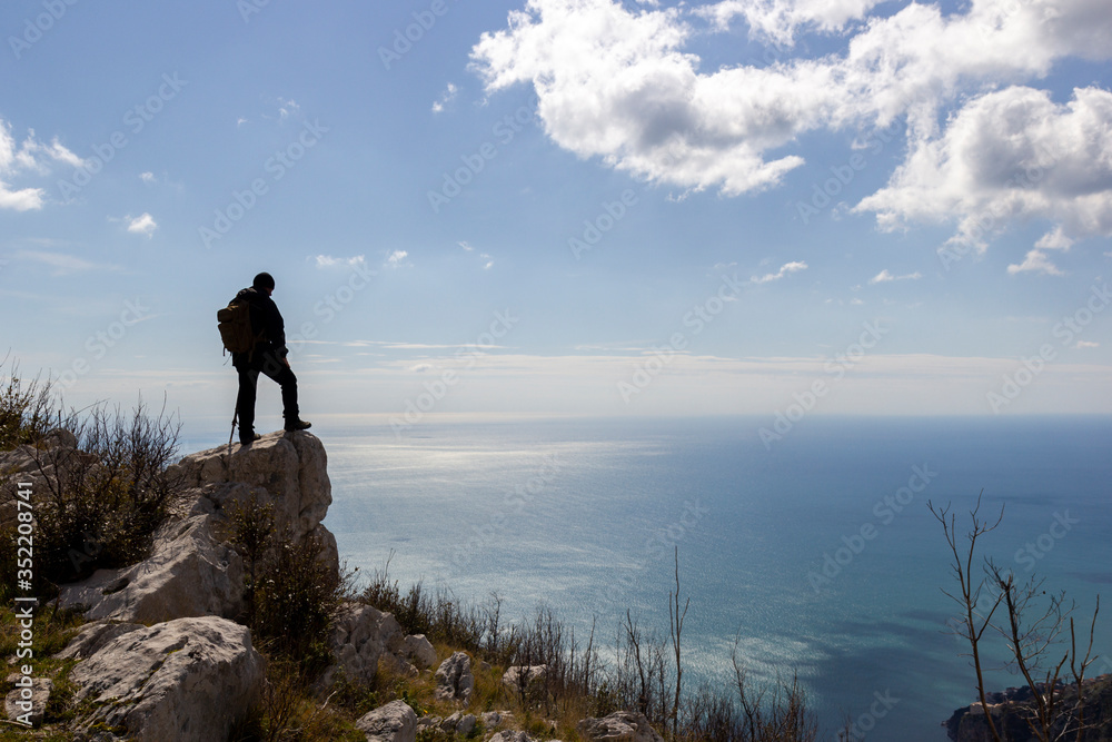 hiker on mountain peak with sea below