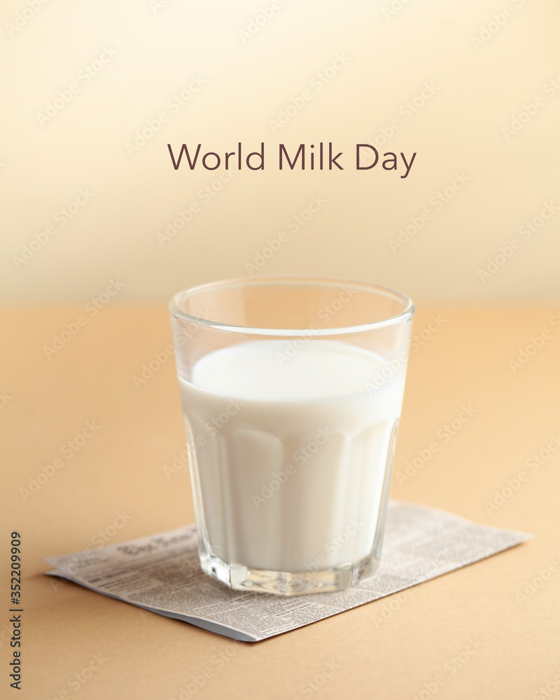 Glass cup with milk on a brown background with the inscription Milk Day. June 1st milk concept. Copy space. Glass cup with milk on a brown background with the inscription Milk Day. June 1st milk concept. Copy space.