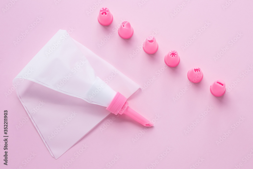Cake decorating tools, the pastry bag with nozzles on pink background for cake decoration. Concept of cooking confectionery with cream. Cake decorating tools, the pastry bag with nozzles on pink background for cake decoration. Concept of cooking confectionery with cream.