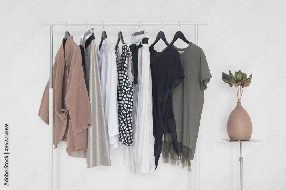 A rack with stylish clothes next to a white wall in the room. Clothing retails concept. Advertise, sale, fashion. A rack with stylish clothes next to a white wall in the room. Clothing retails concept. Advertise, sale, fashion.