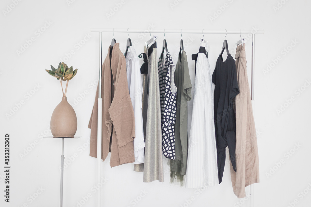 A rack with stylish clothes next to a white wall in the room. Clothing retails concept. Advertise, sale, fashion.