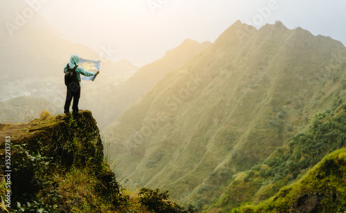 Man with the map staying on top of the mountain rock with gorgeous panorama view over high mountain ranges and deep valley © Igor Tichonow