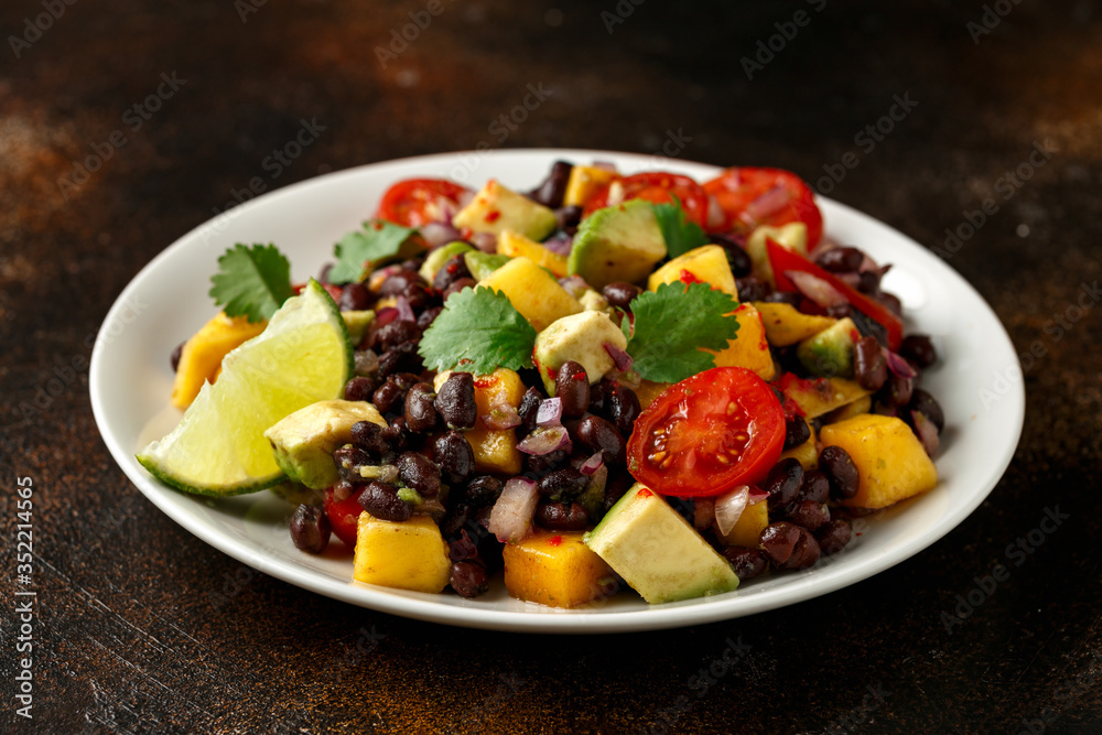Avocado, mango salad with black bean on white plate