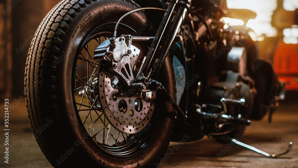 Macro Close Up Wheel Details of a Custom Bobber Motorbike Standing in an Authentic Creative Workshop. Chromed Motorbike Spokes and Disc Brakes Up Close. Macro Close Up Wheel Details of a Custom Bobber Motorbike Standing in an Authentic Creative Workshop. Chromed Motorbike Spokes and Disc Brakes Up Close.