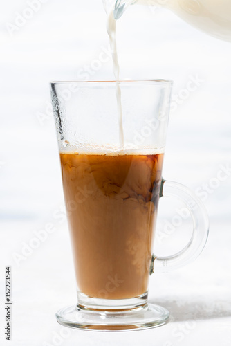 milk is poured into a glass cup with coffee