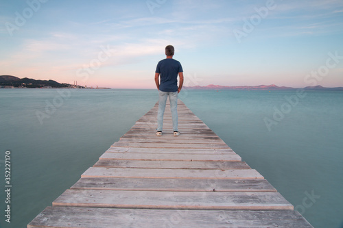 Man on a wooden pier looking toward the sea with silky water on the island of Mallorca