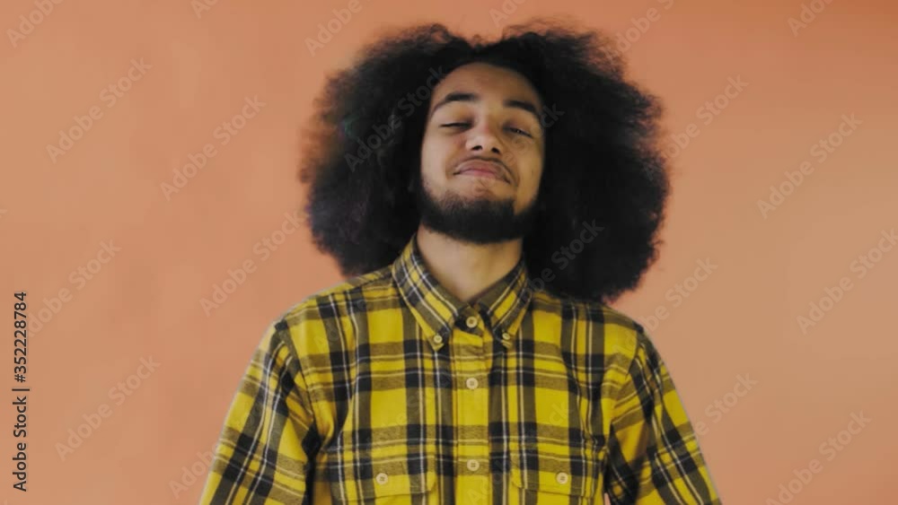 Smiling attractive Afro-American guy showing ok gesture while standing isolated over Orange background. Concept of emotions Smiling attractive Afro-American guy showing ok gesture while standing isolated over Orange background. Concept of emotions