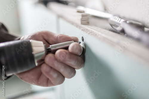 Ein Handwerker schraubt eine Schraube in eine Gipsplatte und montiert sie an der Wand photo
