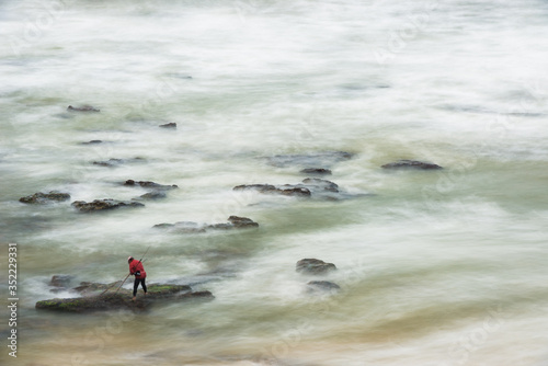 Long exposure photograph of a shellfisherman working on the rocks at Seixo beach, Torres Vedras photo