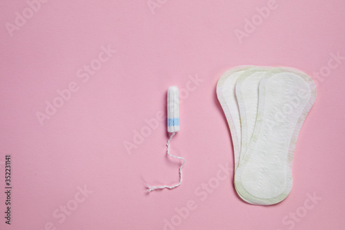 white sanitary cotton pad and feminne tampon on pink background, top view. Feminine hygiene products