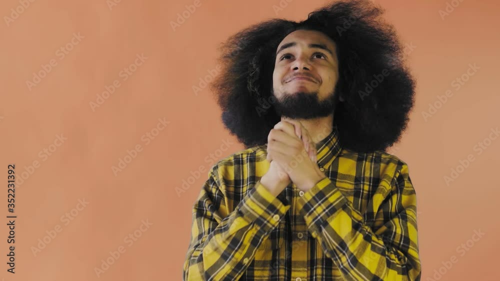 Portrait of praying african american guy keeping fingers crossed and screaming god please on Orange background. Concept of emotions Portrait of praying african american guy keeping fingers crossed and screaming god please on Orange background. Concept of emotions