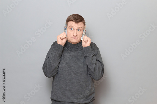 Mature man is covering his ears with money