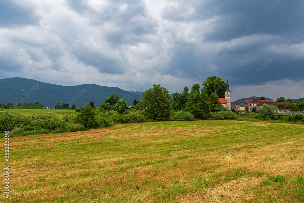 Landscape with mountains and the  village of Pudob with a nice catholic church in the Inner Carniola region, Slovenia