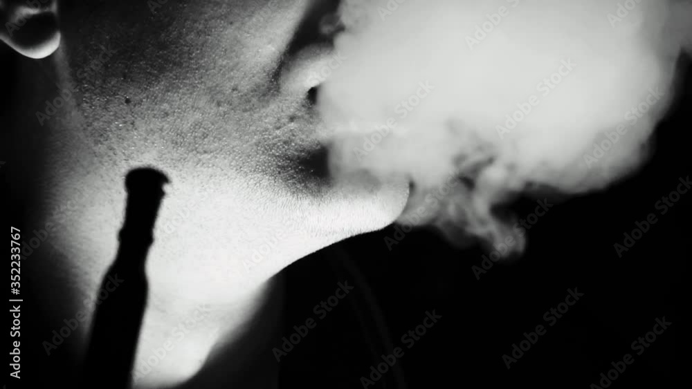 the silhouette of a man on a dark background exhales clouds of smoke the silhouette of a man on a dark background exhales clouds of smoke