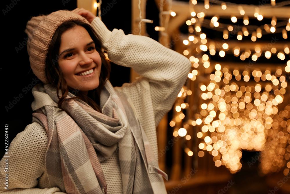 Young woman wearing warm sweater, hat and scarf  outdoors at night. Winter season