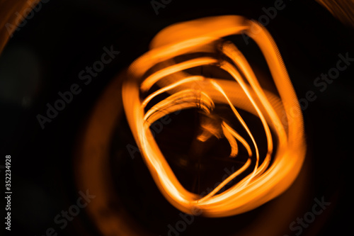 Macro shot of glowing wire of edison light bulb on black background