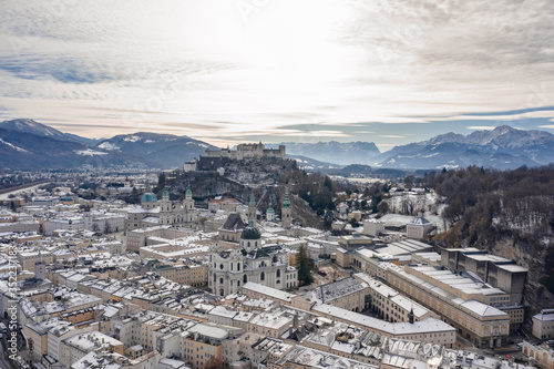 Aerial drone shot view of snowy salzburg city center with view of Cathdrals and fortress in winter