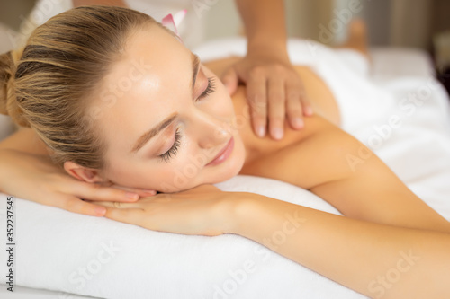 Beautiful woman get massage on back on spa bed at spa salon. Massage therapist massage, treatment back. Customer girl get relaxed, tranquility. Oriental massage in luxury spa room. spa concept
