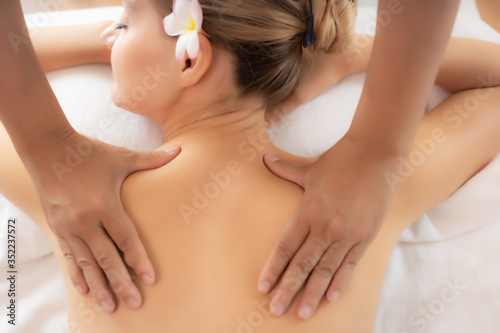 Beautiful woman get massage therapy on back in spa bed at spa salon. Massage therapist massage shoulder and back. Customer girl get relaxed, tranquility Oriental massage in luxury spa room spa concept