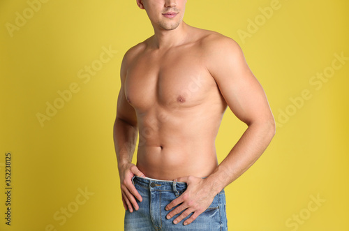 Man with sexy body on yellow background, closeup