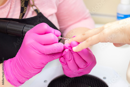 HardWear manicure. manicurist in pink gloves manicures a girl.