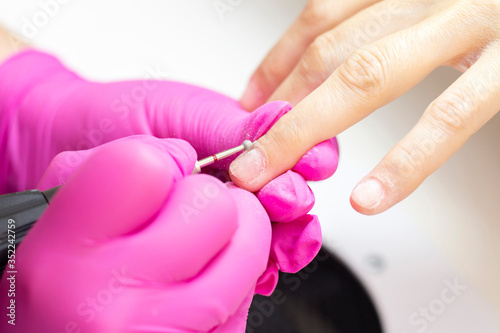 HardWear manicure. manicurist in pink gloves manicures a girl.