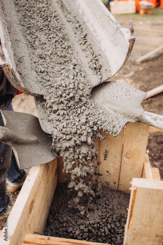 Filling concrete in a wooden box, building the foundation of an apartment building, shovel in concrete