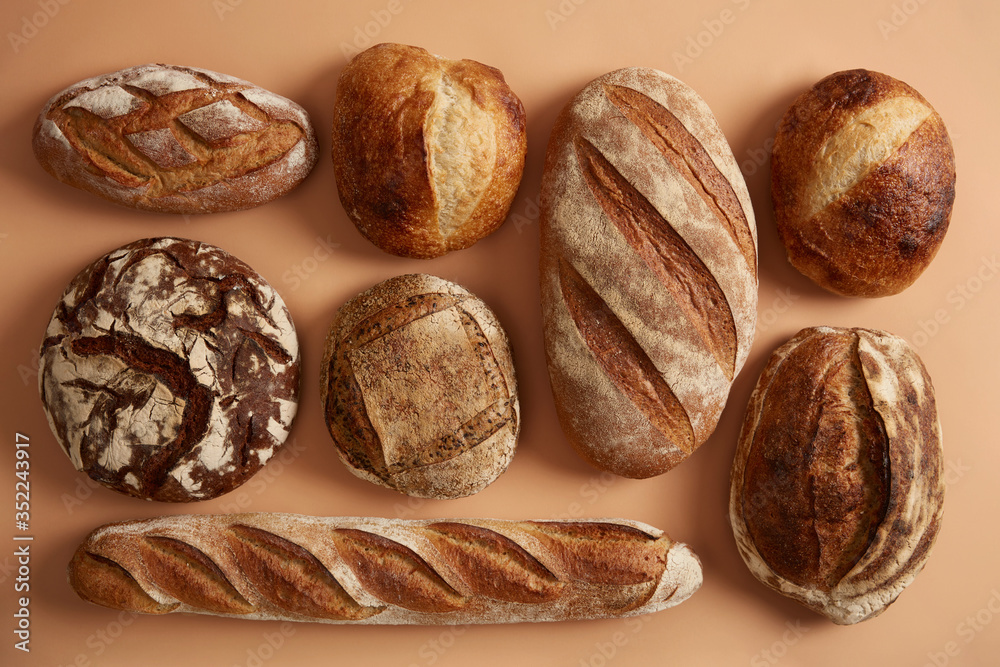 Natural sourdough bread baked with organic flour. Spelt wheat, buckwheat, rye bread isolated over beige background. Bakery and agriculture concept. Nutrient freshly baked products easy to digest Natural sourdough bread baked with organic flour. Spelt wheat, buckwheat, rye bread isolated over beige background. Bakery and agriculture concept. Nutrient freshly baked products easy to digest
