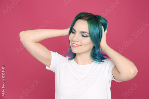 Young woman with bright dyed hair on pink background