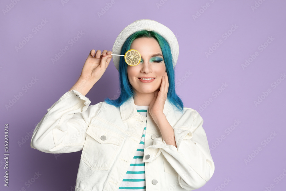 Young woman with bright dyed hair holding candy on lilac background Young woman with bright dyed hair holding candy on lilac background