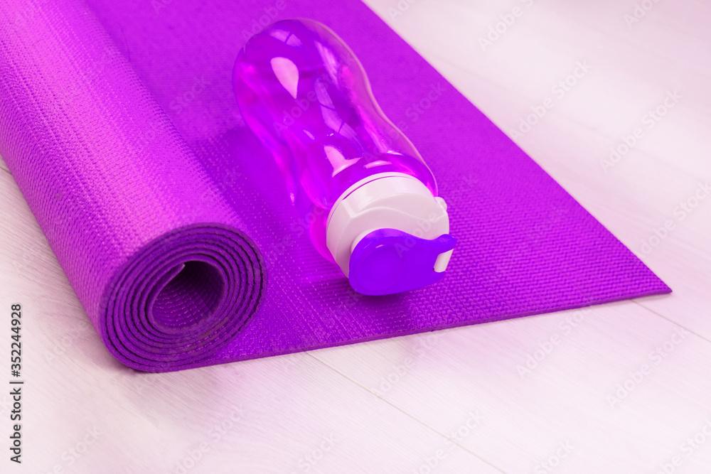 Sports concept. Pink bottle of water and yoga mat.
Sports concept. Pink bottle of water and yoga mat.