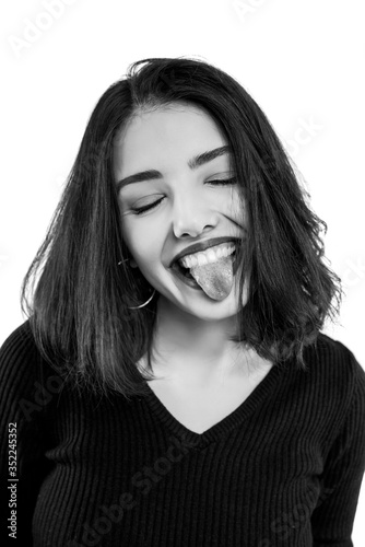 Black and white young woman showing tongue isolated on white background.