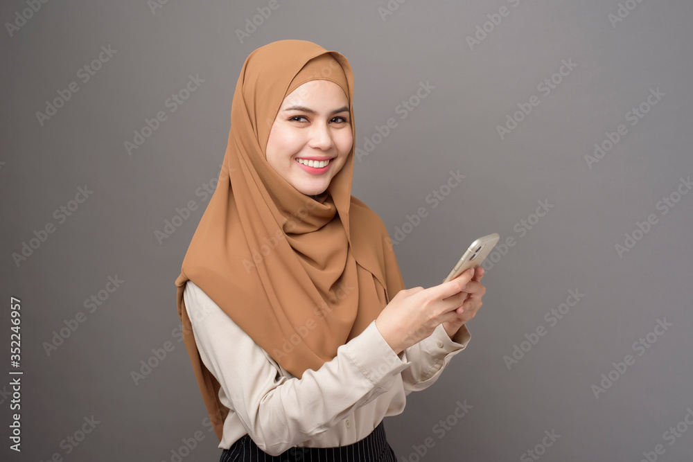 Portrait of beautiful woman with hijab using cellphone on gray background Portrait of beautiful woman with hijab using cellphone on gray background