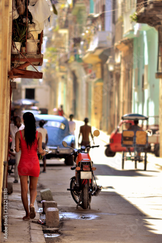 young woman wearing a red skirt walking on a street of La Havana, Cuba. © Ion