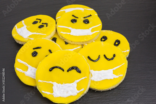 yellow emoji cookies with anti-virus face mask as protection against corona pandemic